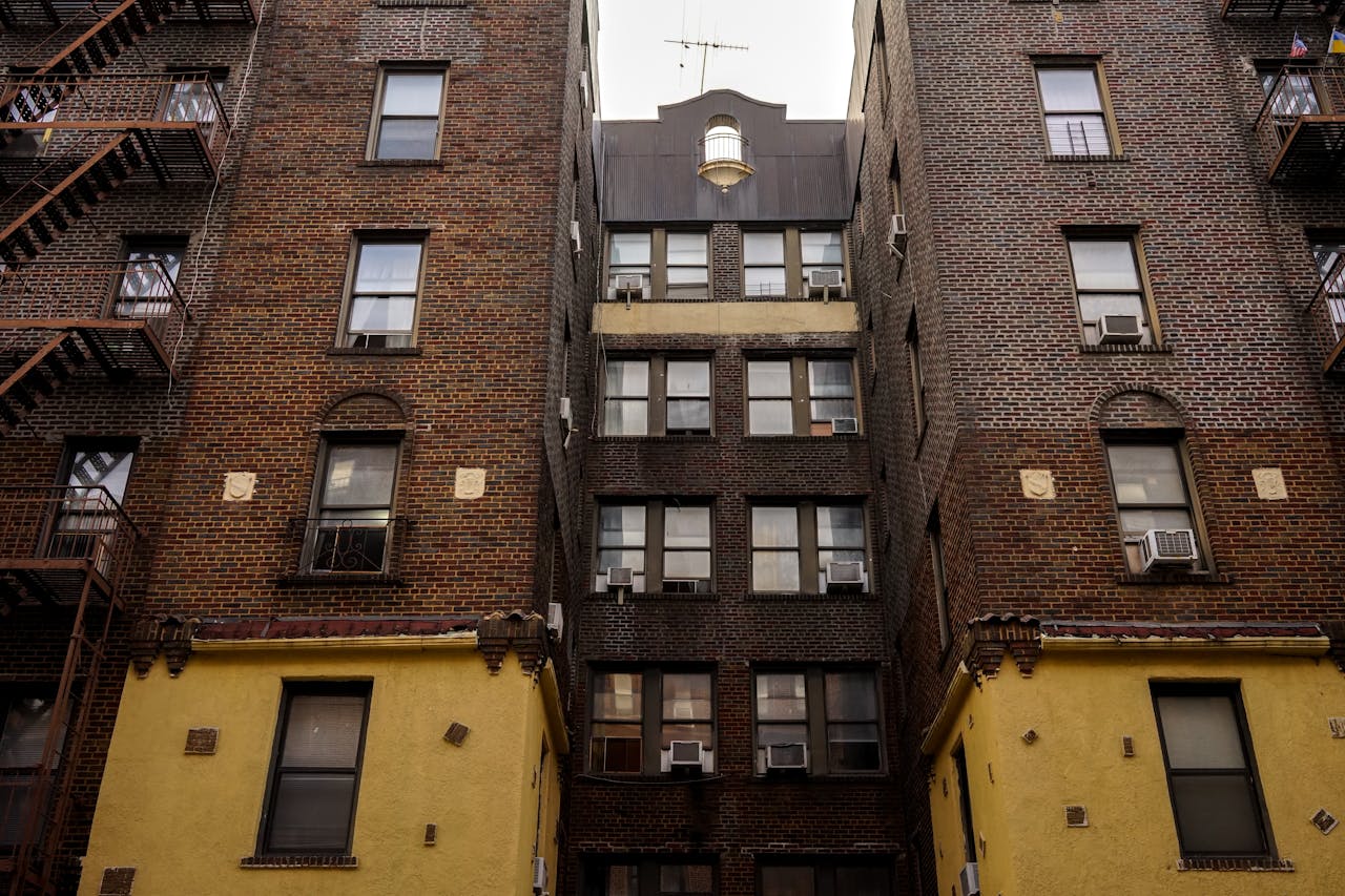 Low-angle view of urban brick apartment buildings with fire escapes, embodying classic city architecture.